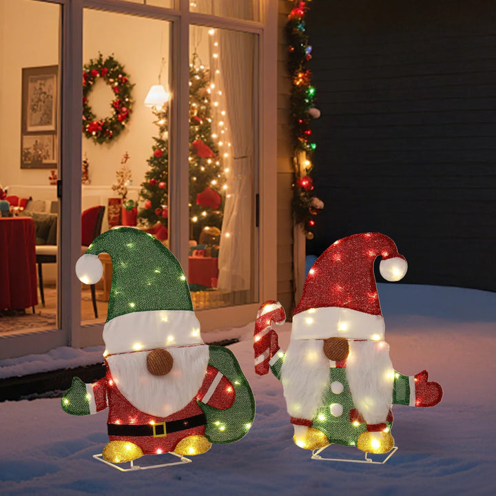 Two lit Christmas gnome figures in garden